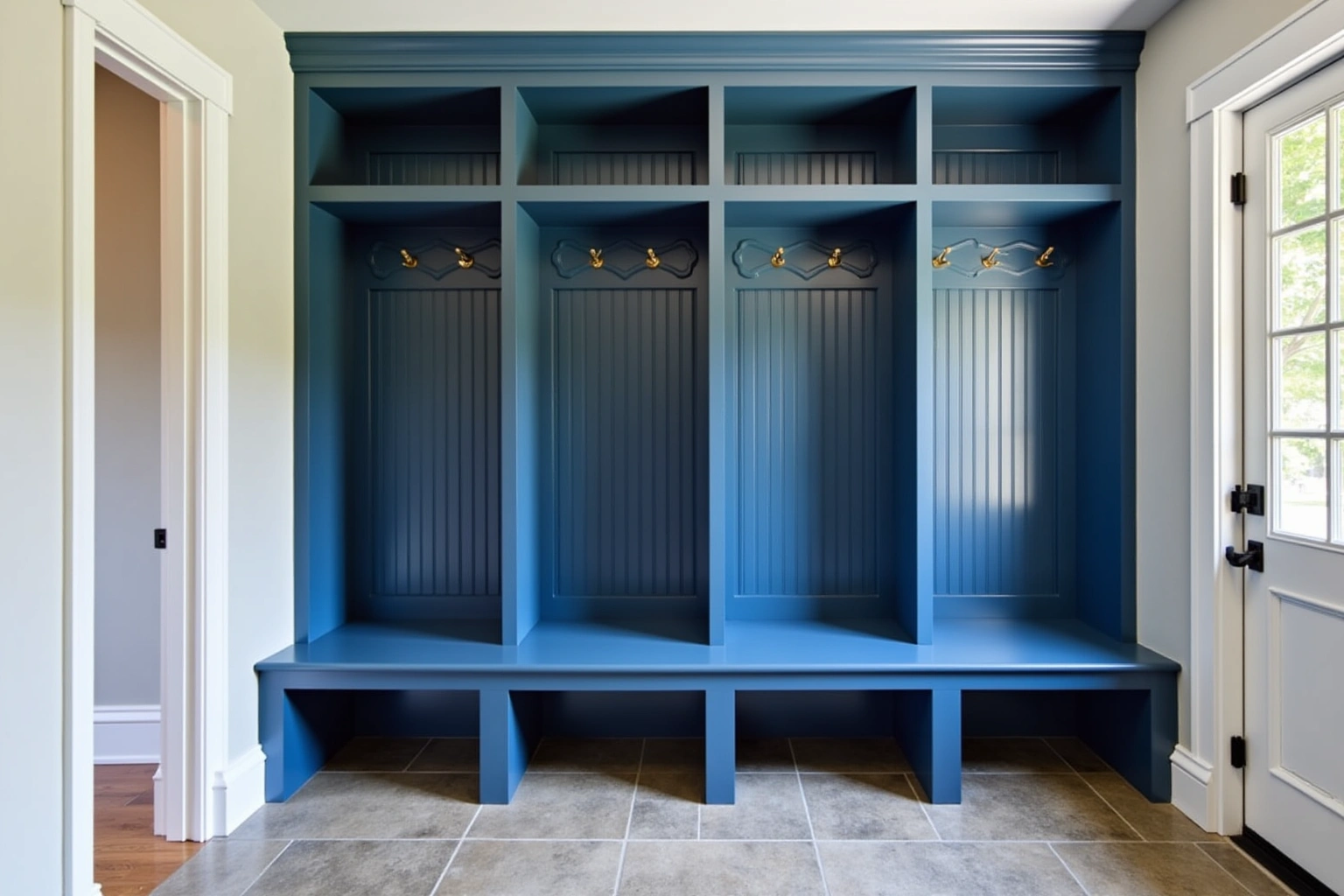 Four deep blue mudroom lockers with beadboard backs, brass hooks, a shared bench and open cubbies above.